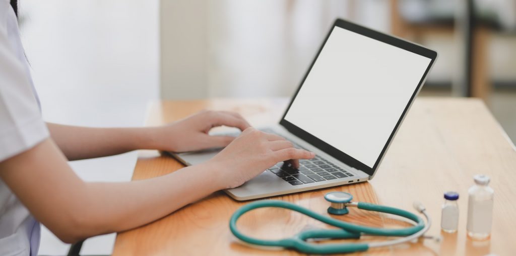 laptop-near-teal-stethoscope-in-wooden-table